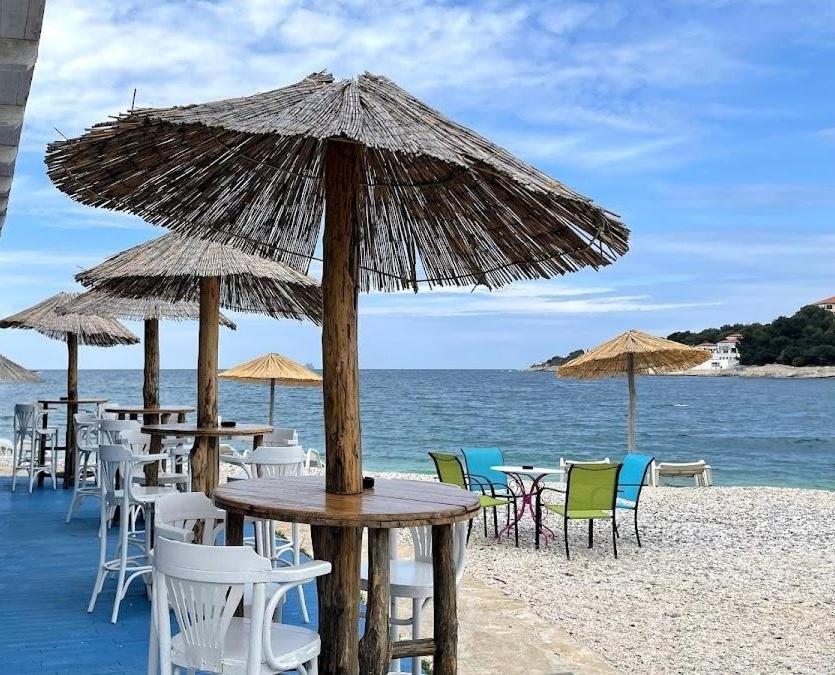 a group of tables and chairs with umbrellas on the beach at Apartment MONAS I in Pješčana Uvala 