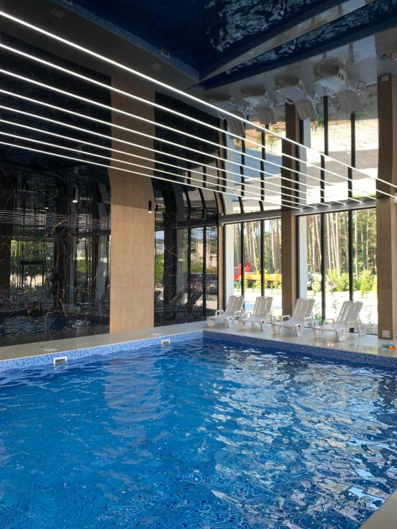 a large swimming pool with white chairs in a building at Pobierowo - Baltic Apartments in Pobierowo