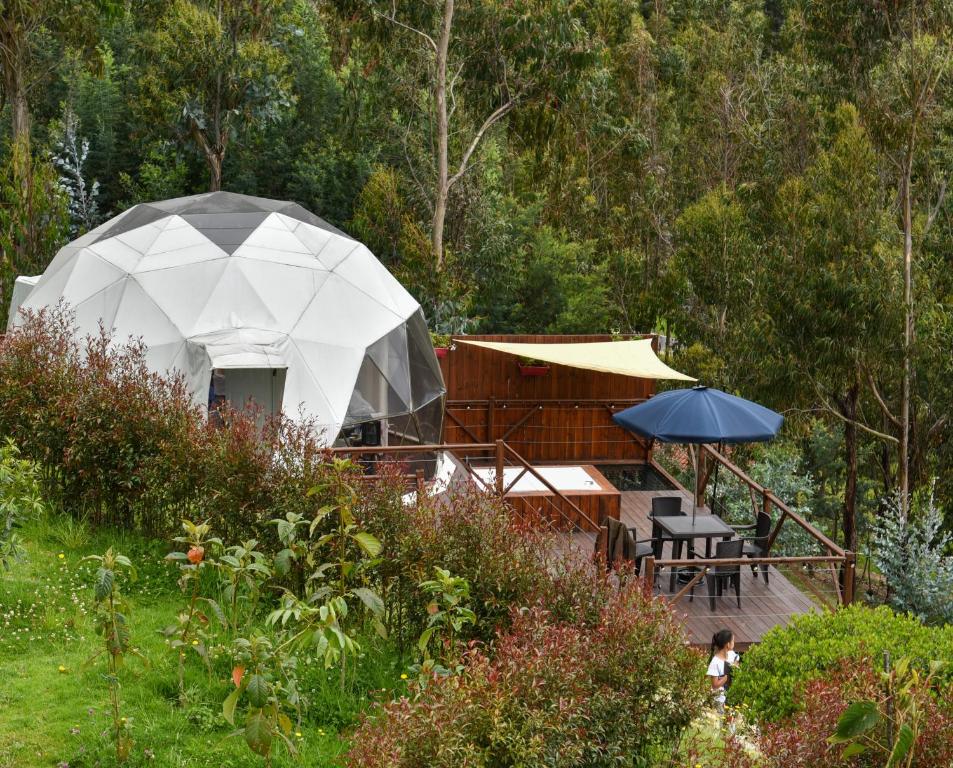 a tent in a garden with a table and umbrella at Golden Glamping in Guatavita