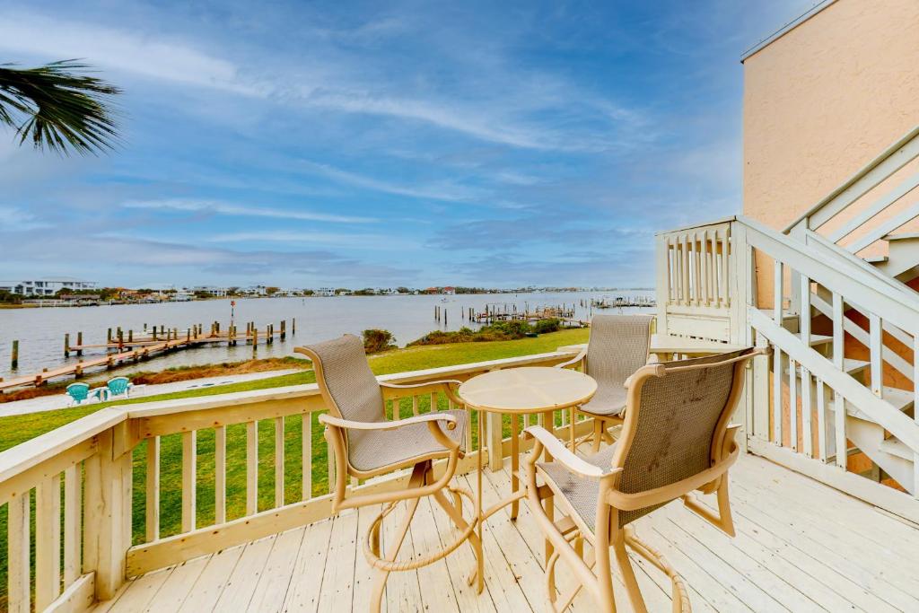a balcony with a table and chairs and a view of the water at Treehouse Townhome in Pensacola Beach