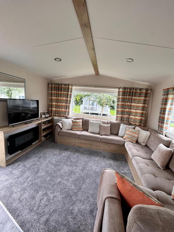 Cosy Caravan في Ulrome: غرفة معيشة مع كنب وتلفزيون بشاشة مسطحة
