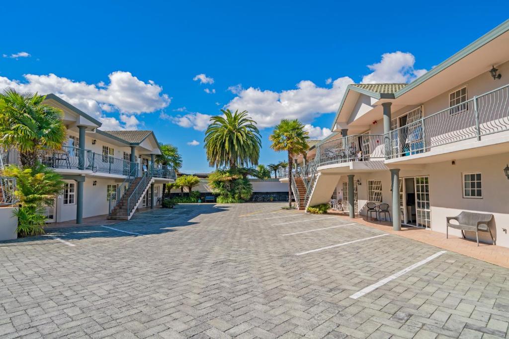 a driveway in front of a building with palm trees at Silver Fern Rotorua Suites & Spa in Rotorua