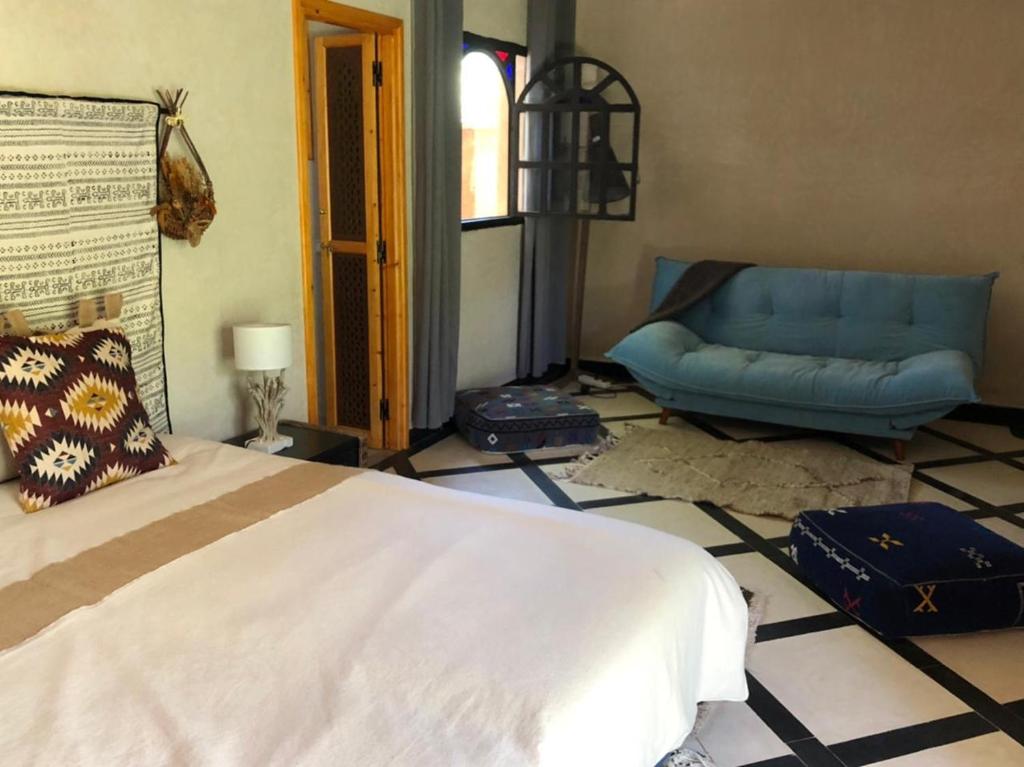 a bedroom with a bed and a blue chair at villa Oulad Hassoune in Mellah Bakka