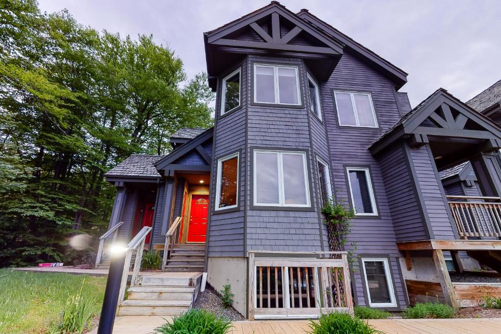 een zwart huis met een rode deur bij Summit Solitude & Latitude Adjustment in Jay