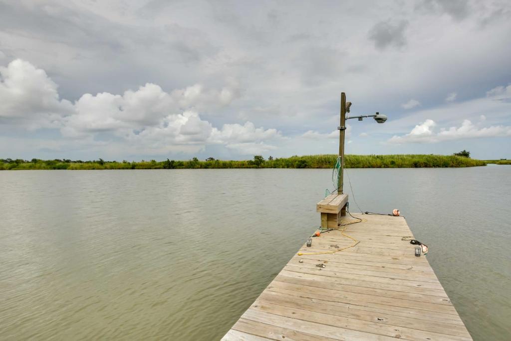 a wooden dock on a lake with a cross on it at Golden Meadow Getaway Waterfront Retreat with Deck in Golden Meadow