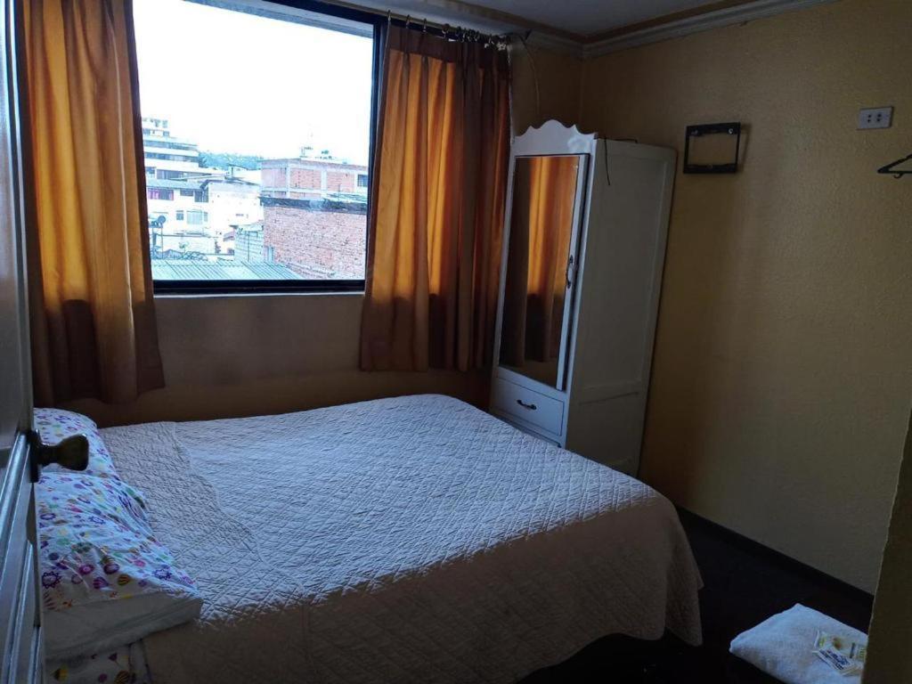 een kleine slaapkamer met een bed en een raam bij Hotel Presidente in Quito