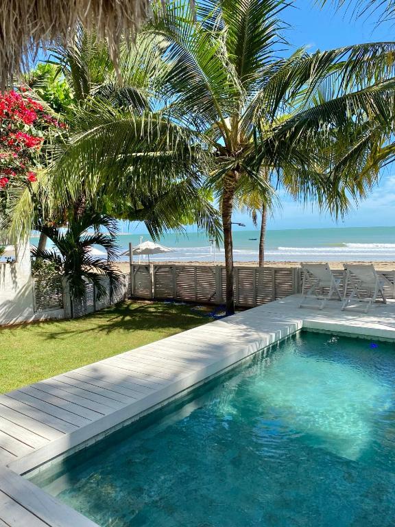 a swimming pool with palm trees and the beach at Nordestina Casa de Mar in Icaraí