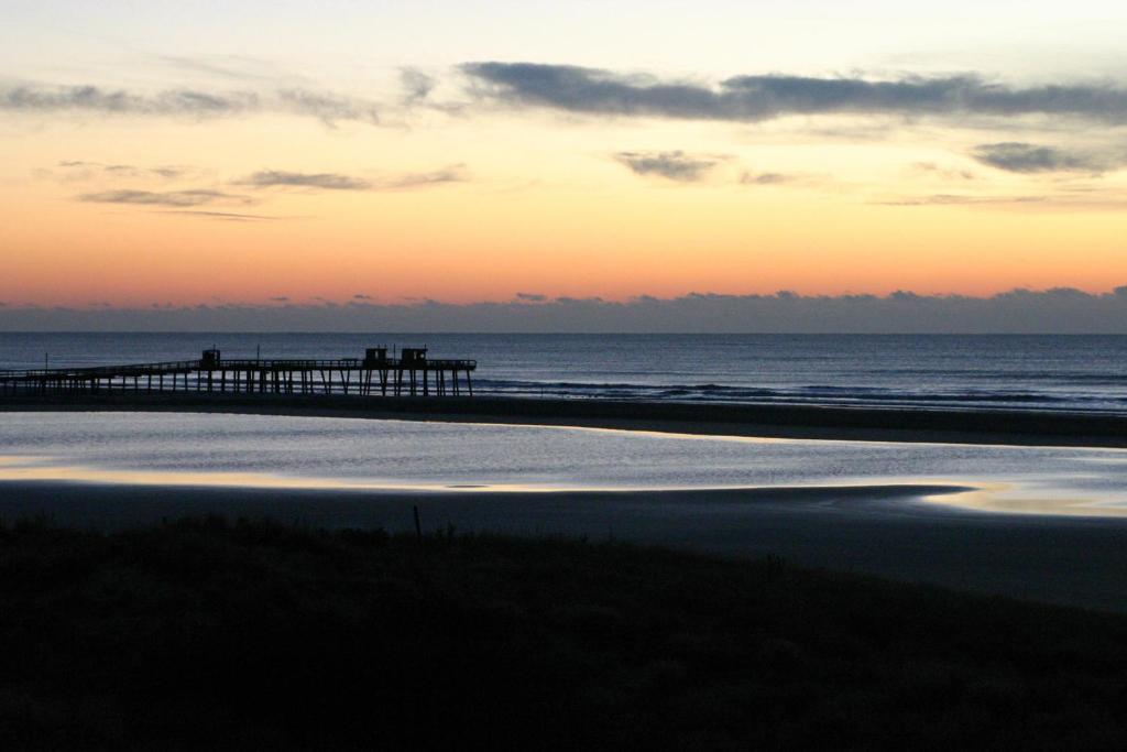 a beach with a pier and the ocean at sunset at Nassau Inn in Wildwood Crest