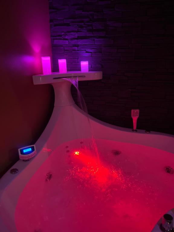 a table with pink lights on top of a bath tub at HomeSparadise Loveroom in Besançon