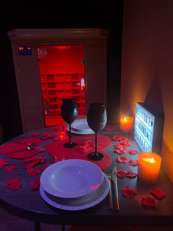 a table with two plates and two glasses and a candle at HomeSparadise Loveroom in Besançon