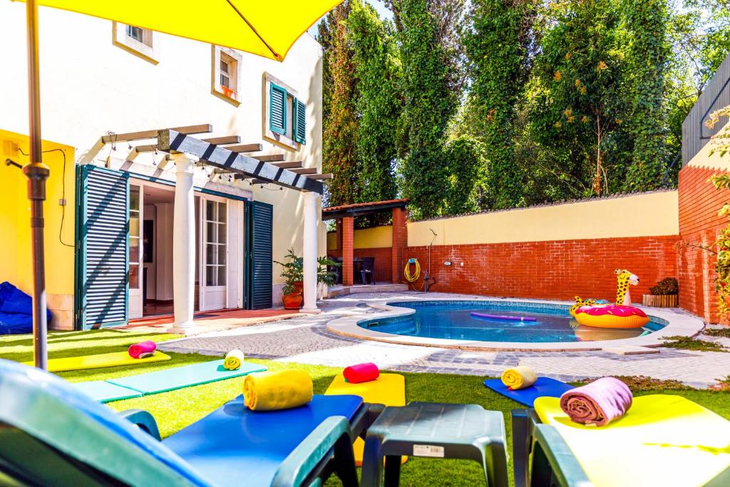 une cour avec une piscine entourée de chaises et d'un parasol dans l'établissement Jacuzzi, garden, pool & barbecue beach House, 15mn from Lisbon center, à Oeiras