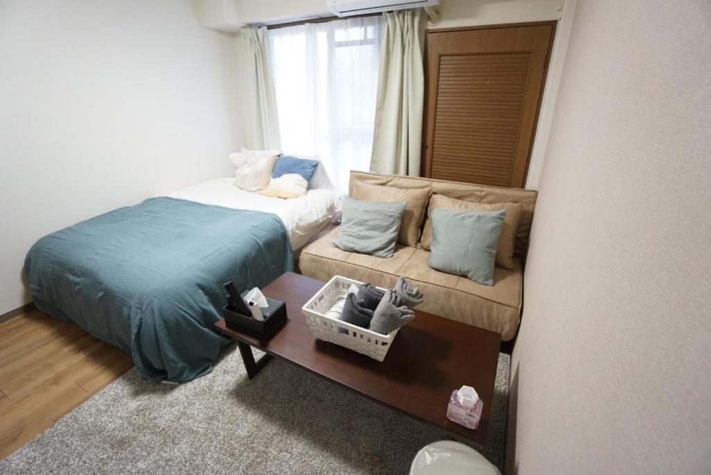 um quarto com uma cama, um sofá e uma janela em Apartment Febbraio Motomachi 503 em Osaka