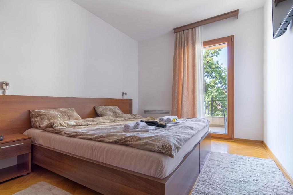 a bedroom with a bed and a large window at Duma Apartmani Vrnjačka Banja in Vrnjci