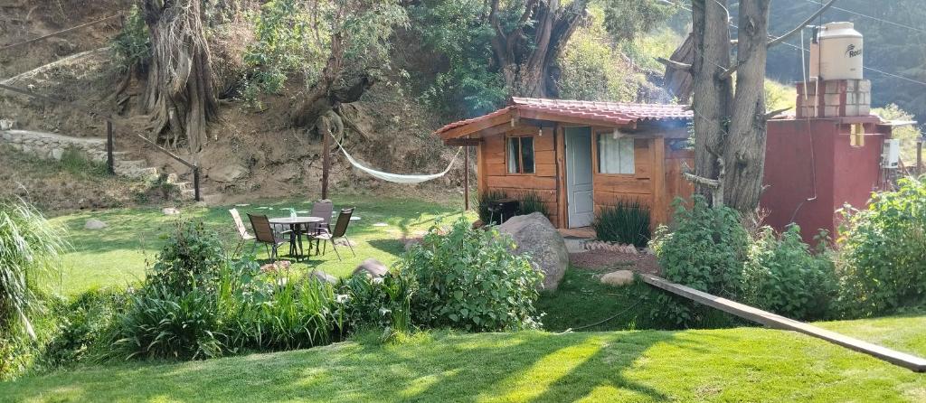 Cabaña pequeña con mesa y sillas en un patio en Cabaña del Río, en San Pedro Atlapulco