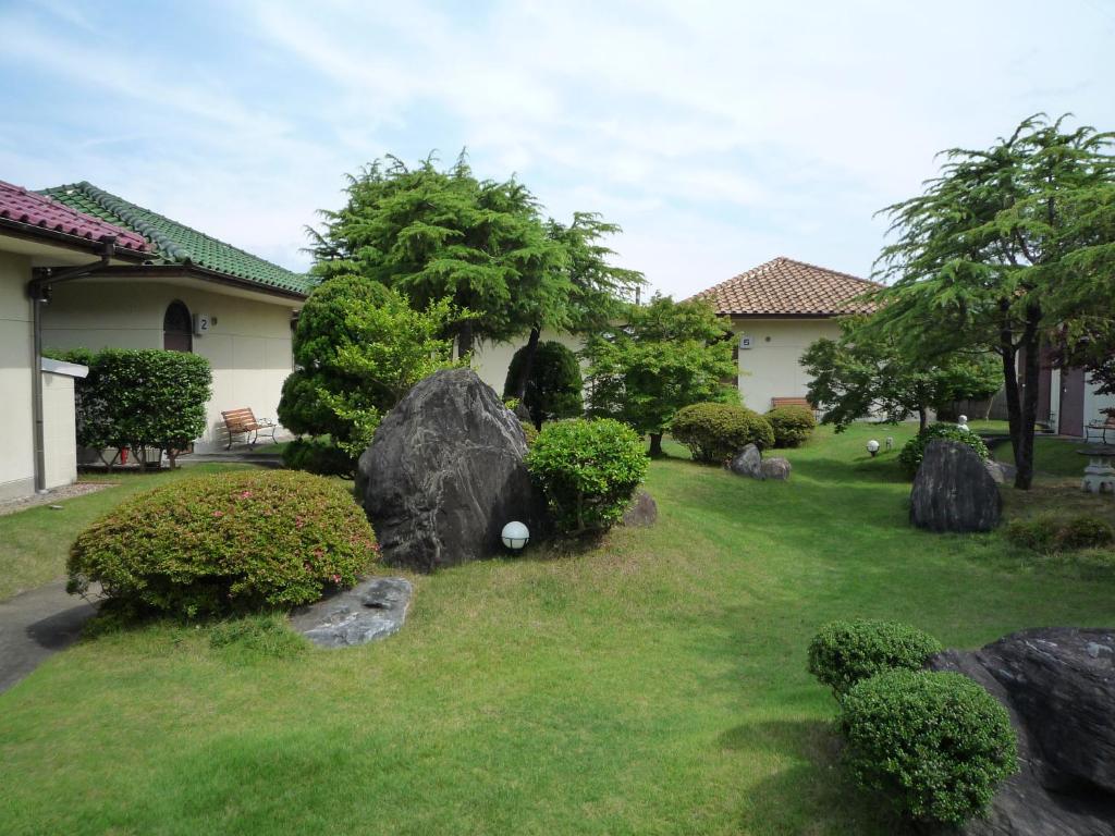 a garden with rocks and bushes and a house at Tabi No Yado Harusame in Kumano