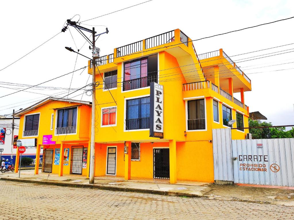 佩德納萊斯的住宿－HOTEL PLAYAS PERDERNALES ECUADOR，街道边的黄色建筑