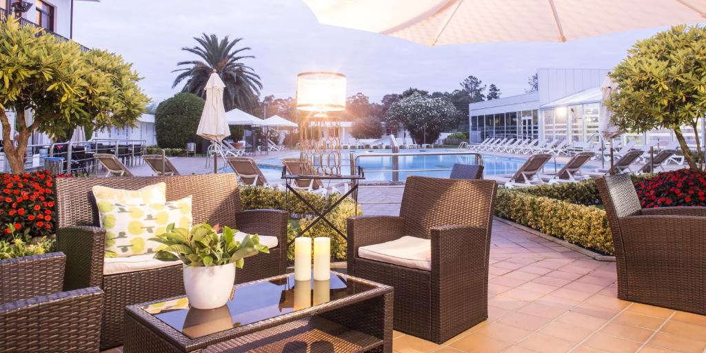 a patio with wicker chairs and tables and a pool at Nuevo Astur Spa in Sanxenxo