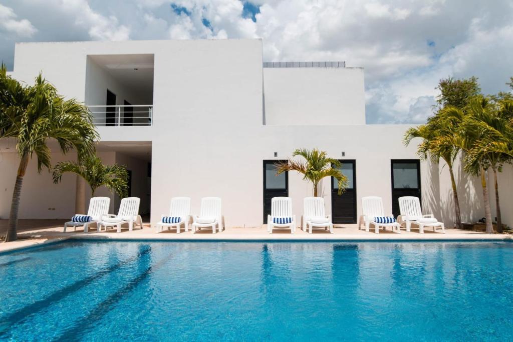 a villa with a swimming pool and chairs and a house at Hotel & Suites Yuca Ville Siglo XXI in Mérida