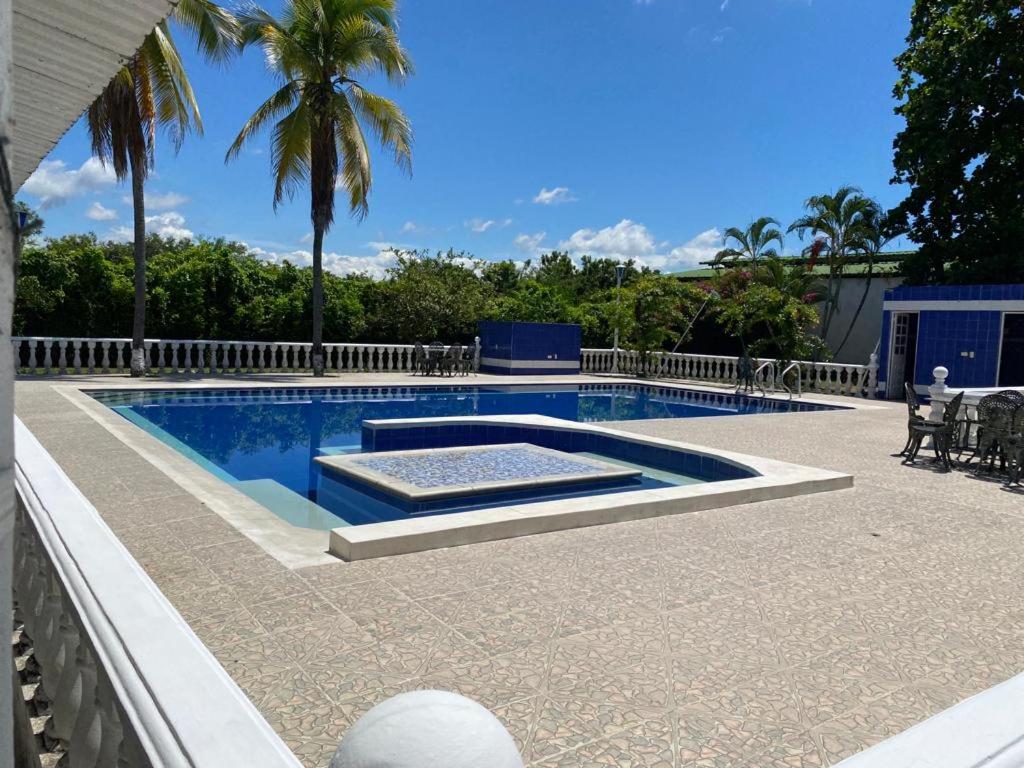 a large swimming pool with a patio and palm trees at Finca Esperanza - Girardot - El Espinal in El Espinal