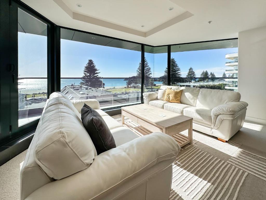 a living room with two white couches and a view of the ocean at Mount Eleven Fabulous Sea Views in Mount Maunganui
