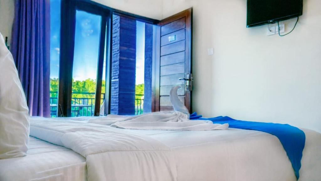 Habitación de hotel con cama y ventana en Ratu Guest House en Kuta