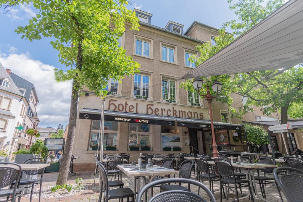 a restaurant with tables and chairs in front of a building at Hotel Herckmans in Ettelbruck