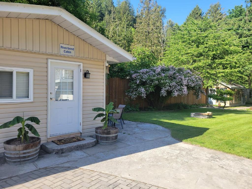 een huis met een witte deur en een tuin bij Riverbend Guest House in Chilliwack