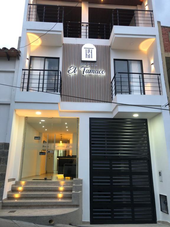 a white building with a black door and stairs at Hotel el tamaco in Ocaña