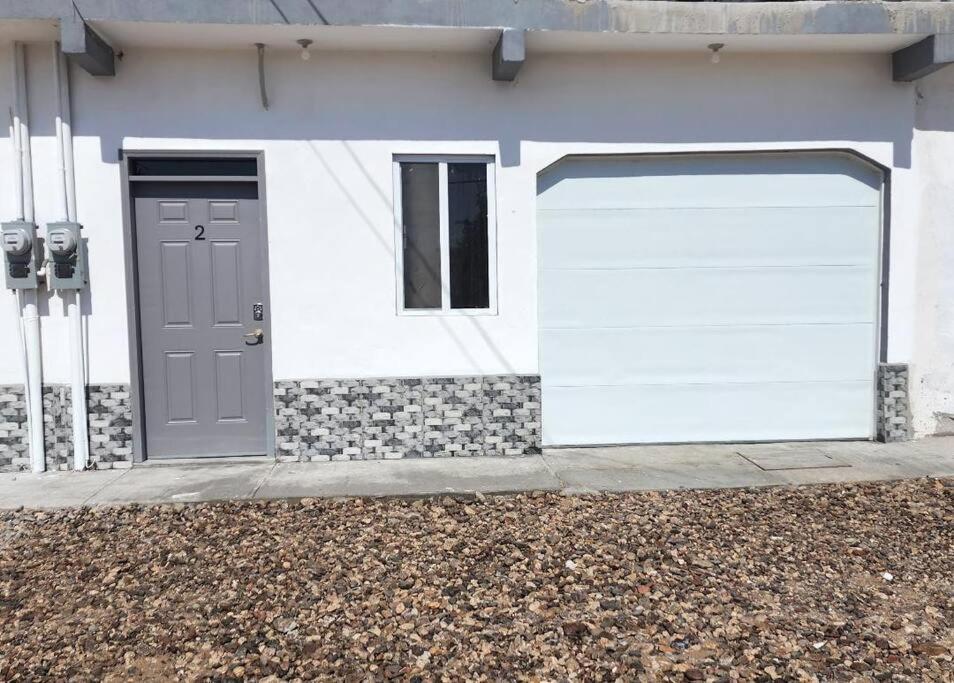 a white house with two garage doors and a parking meter at Stay Here! 10 MIN FROM BEACH! 2 bedroom house in Puerto Peñasco