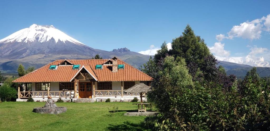 a house with a snow covered mountain in the background at Rumipaxi Lodge in Latacunga