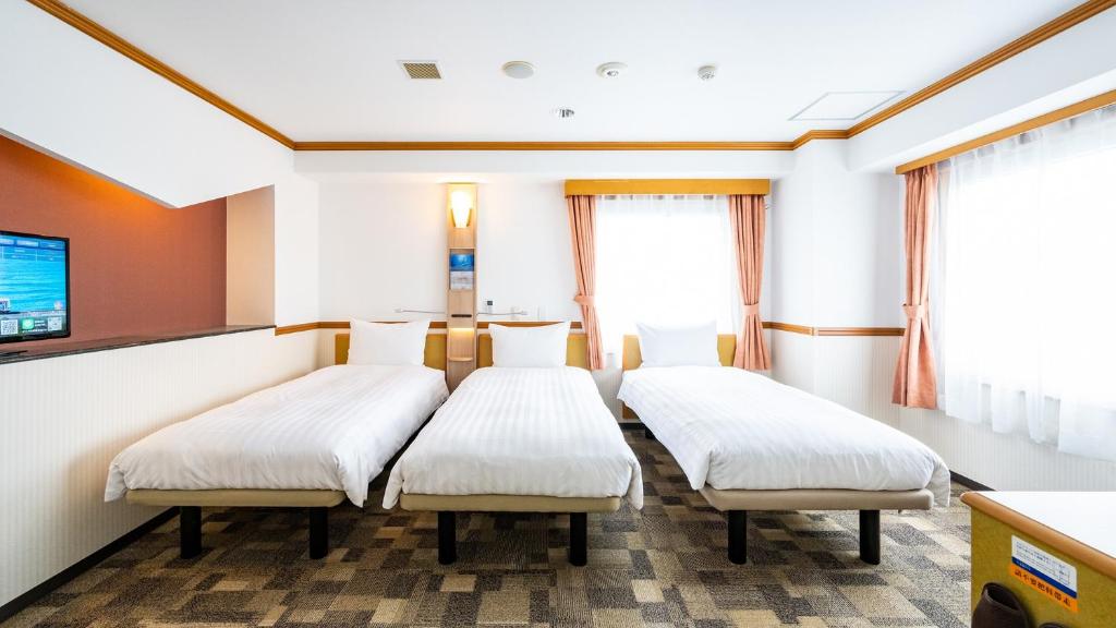 a hospital room with two beds and a tv at Toyoko Inn Chubu International Airport No1 in Tokoname