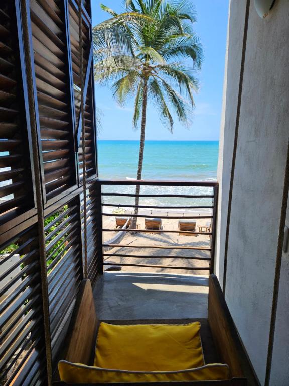 a balcony with a view of the beach and a palm tree at Makao Beach Hotel in Palomino
