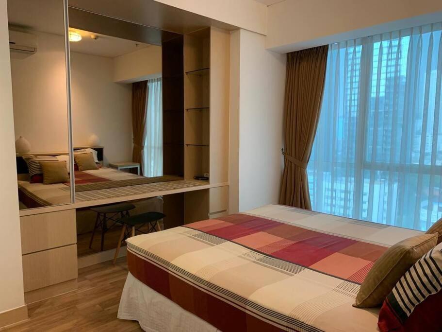 Schlafzimmer mit einem Bett, einem Spiegel und einem Schreibtisch in der Unterkunft 2BR for Business Traveller at Sky Garden in Jakarta