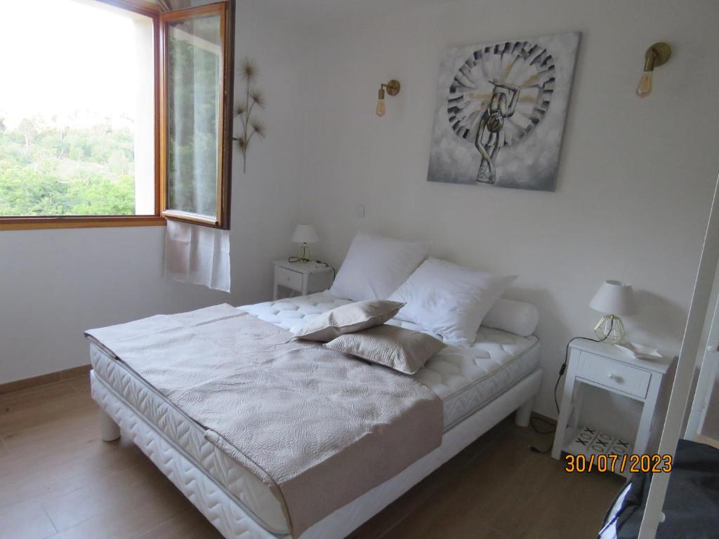 a white bedroom with a bed with a clock on the wall at l'altore di savaghju in Vivario