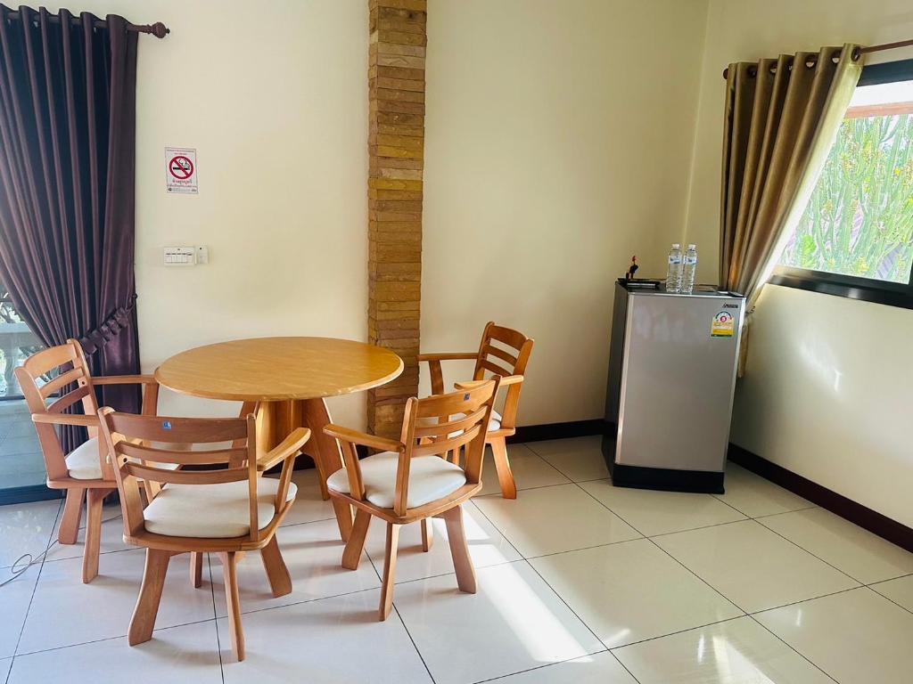 una sala da pranzo con tavolo, sedie e frigorifero di House of Garden Resort a Chiang Rai