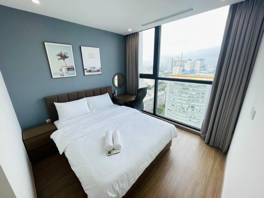 1 dormitorio con cama blanca y ventana grande en VNRooms - 2BR Vinhomes Skylake near Shopping Mall, en Hanói