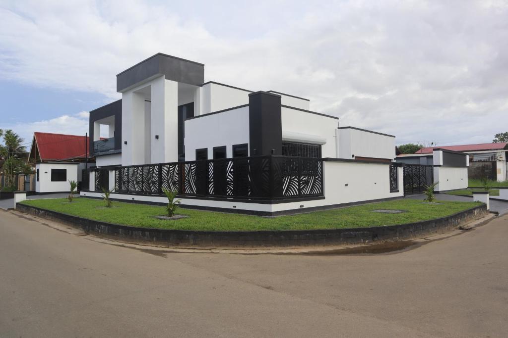 a white house with a black balcony on a street at Empire Villa Paramaribo Noord 1 in Paramaribo