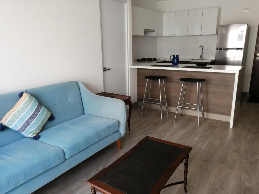 a living room with a blue couch and a kitchen at Cómodo y cálido departamento en San Isidro in Lima