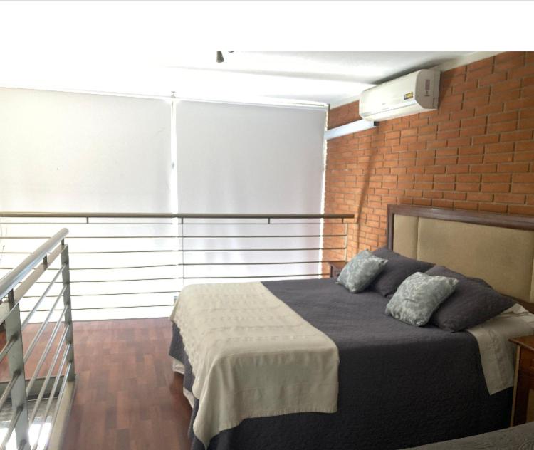 1 dormitorio con cama y pared de ladrillo en Espacio M Providencia, en Santiago
