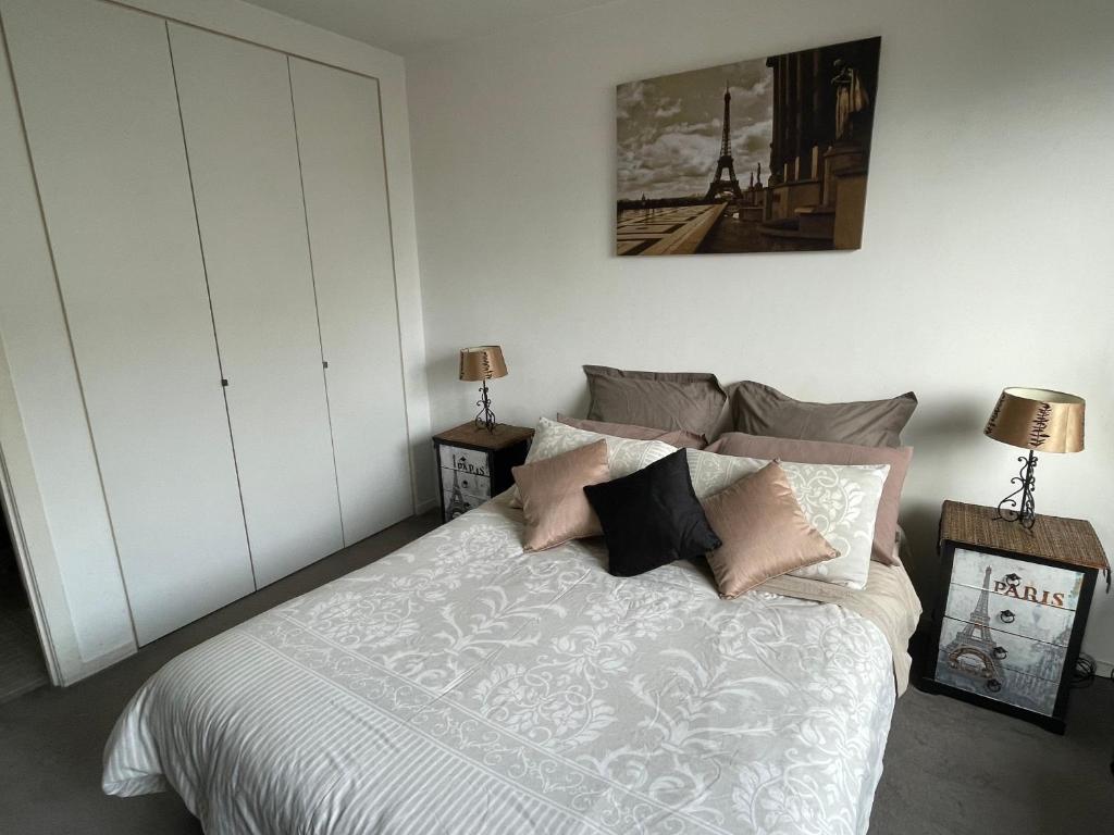 a bedroom with a bed with white sheets and pillows at Chic Fitzroy Street Apartment in Melbourne