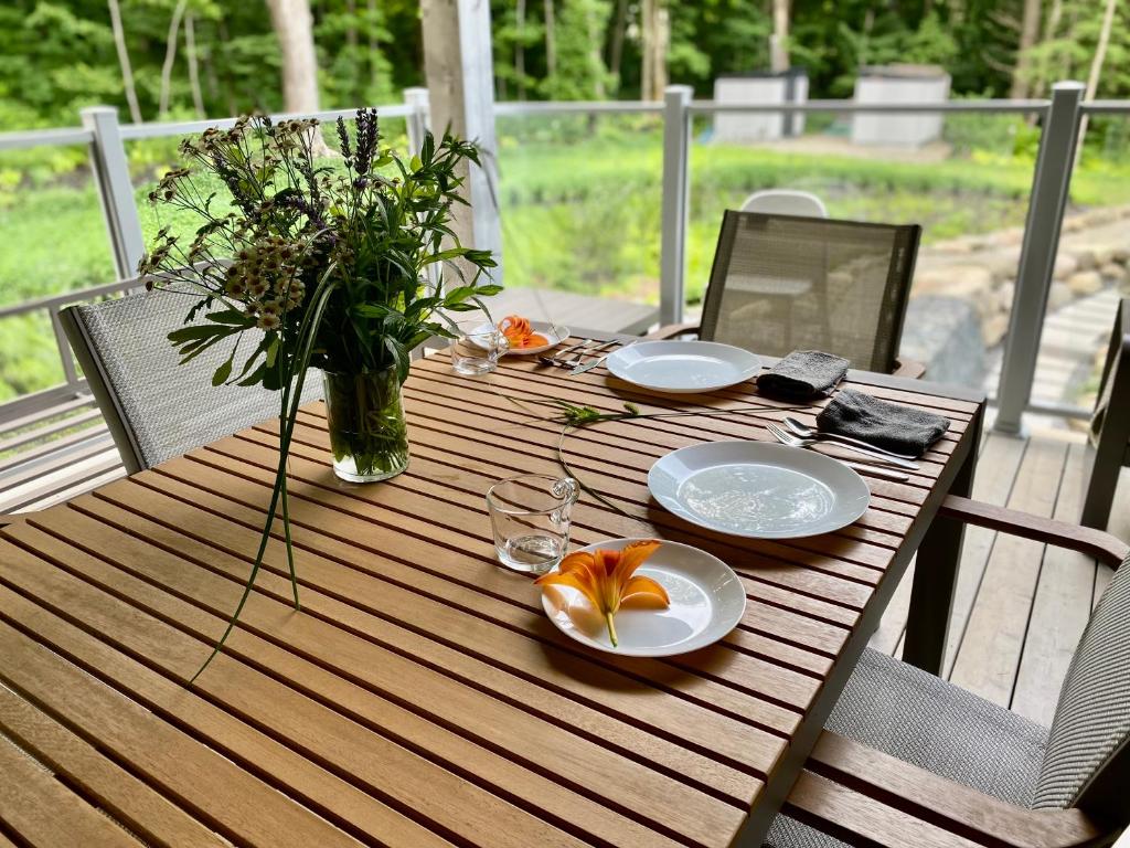 a wooden table with plates and a vase of flowers at Le Camp Caché Shefford in Shefford