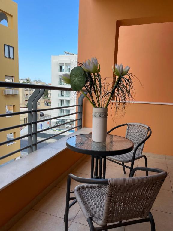 a table and chairs on a balcony with a vase with flowers at VIP Resort Apartment on Makenzie Beach in Larnaca