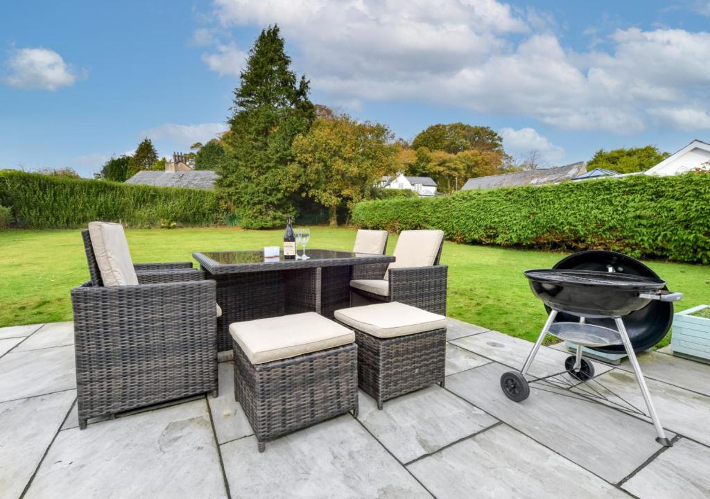a patio with a bbq grill and chairs at Sunnydale in Llanbedrog