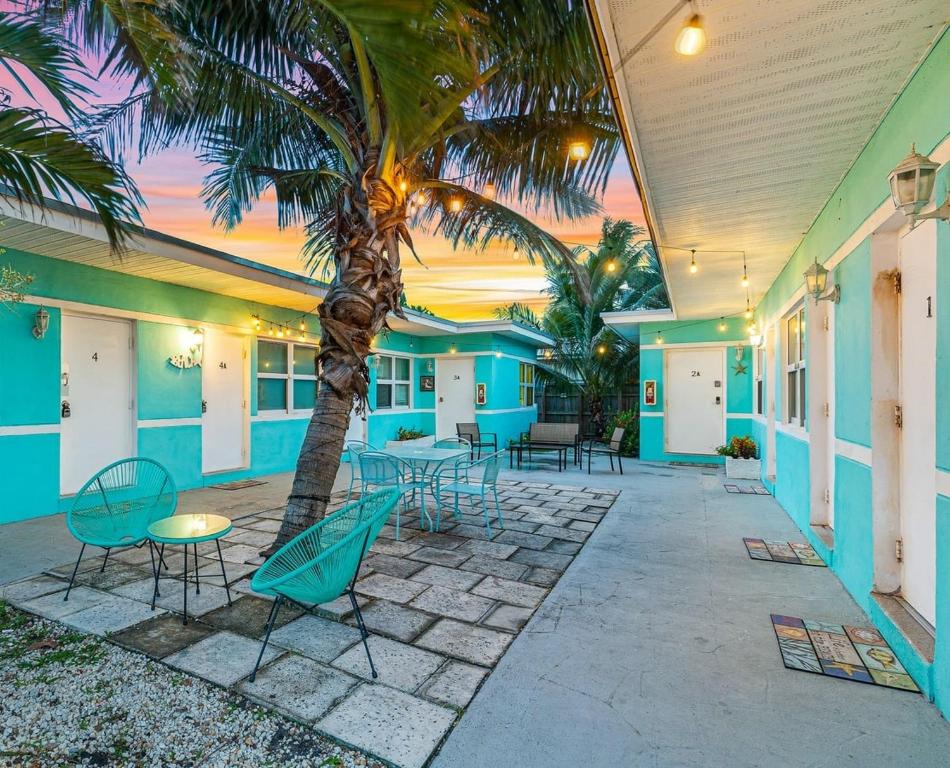 a patio with tables and chairs and a palm tree at Hollywood Broadwalk Holiday Retreat Dania Beach in Hollywood