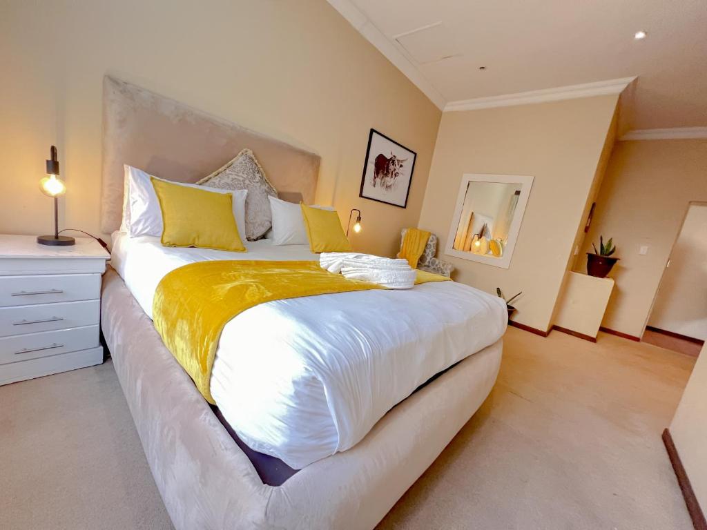 a bedroom with a large bed with yellow and white sheets at Covesto Guesthouse - Waterkloof in Pretoria