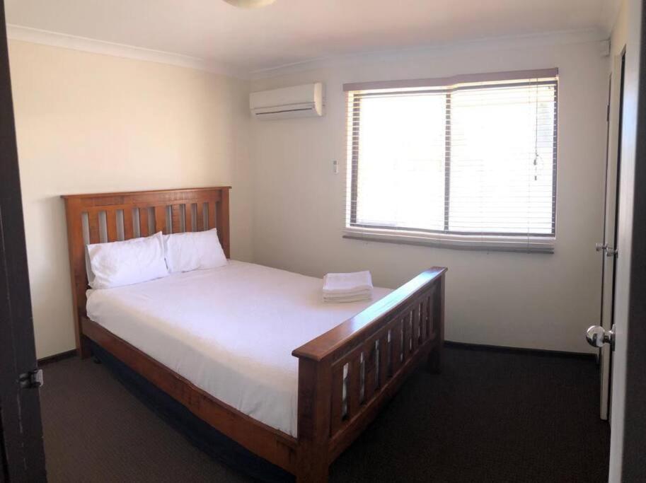 a bedroom with a wooden bed with a window at Piccadilly Accommodation in Kalgoorlie
