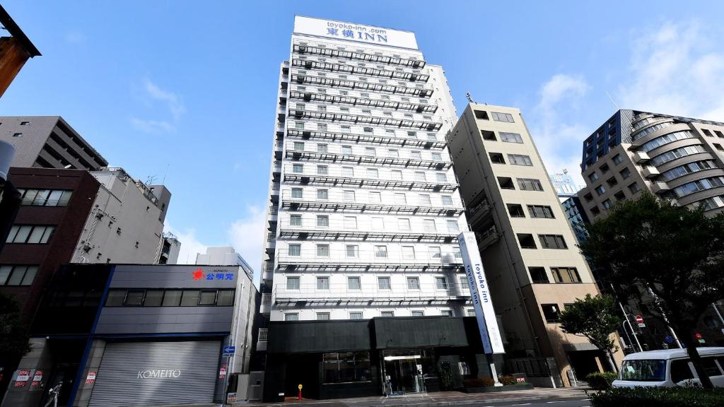 神戶的住宿－Toyoko Inn Kobe Sannomiya eki Shiyakusho Mae，一座高大的建筑,旁边有一个标志