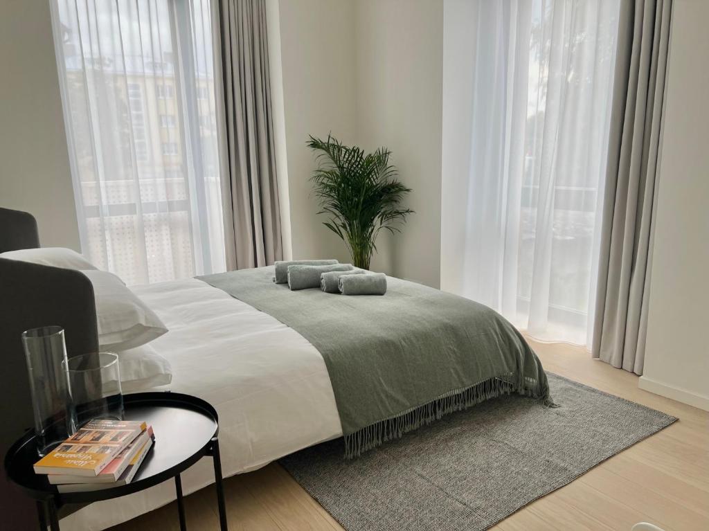 a bedroom with a bed and a table and windows at Brand new city centre apartment, free parking spot in Tallinn