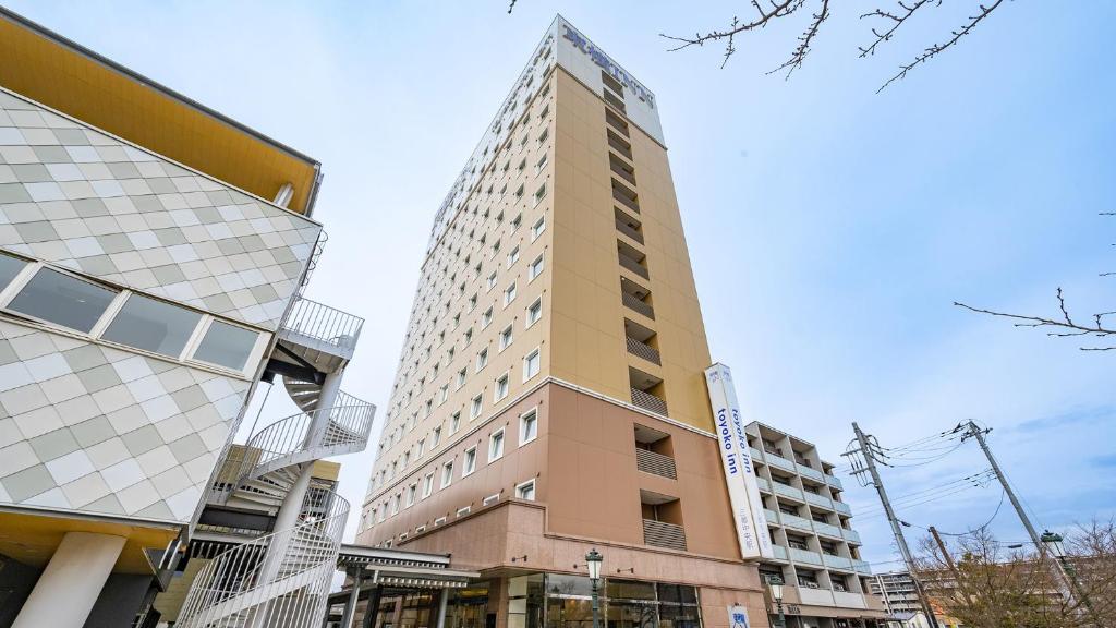wysoki budynek w środku dwóch budynków w obiekcie Toyoko Inn Misato-chuo Ekimae w mieście Misato