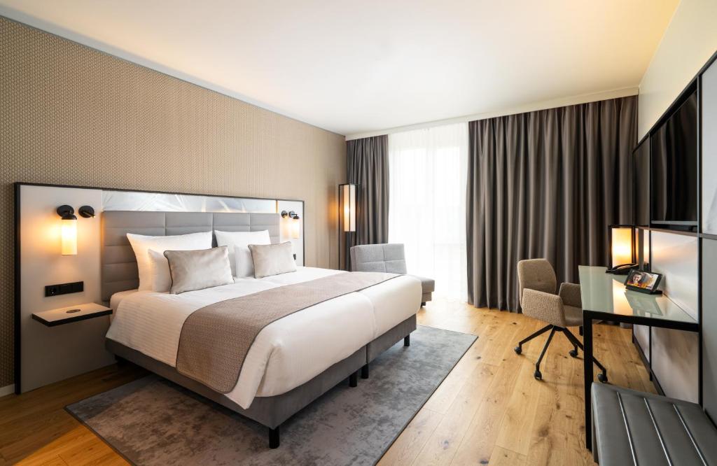 a hotel room with a large bed and a desk at Leonardo Royal Hotel Cologne Bonn Airport in Cologne